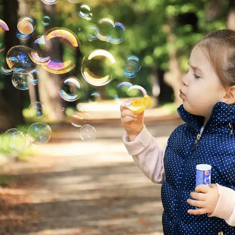 super suds little girl blowing soap bubbles.